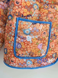 Detailed macro view of quilted floral cotton fabric with blue contrast piping and pocket