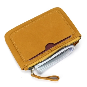 Detail of orange leather wallet showing front card slot and bronze metal zipper closure