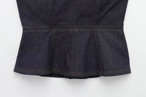 Detail of dark blue denim jacket waist featuring precision double stitching and peplum hem