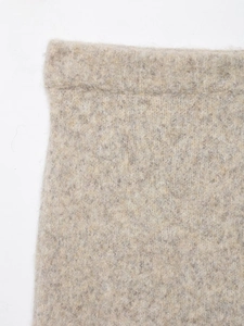 Gros plan sur la maille chinée avoine et les coutures détaillées d'une jupe midi