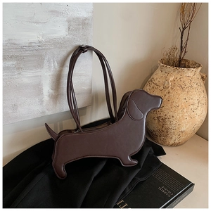 Detailed close-up of brown dachshund dog-shaped leather shoulder bag on a stack of books
