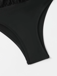 Detailed close-up of double-stitched crotch and lace texture on black swimsuit