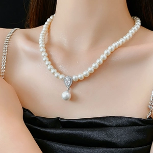 Detail of elegant pearl necklace featuring a drop zircon pendant on a model in evening dress