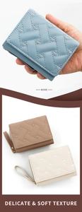 Detail view of woven PU leather texture and embroidered heart on women's trifold wallet