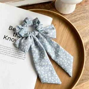 Detailed shot of a blue floral scrunchie with long ribbon tails on a magazine