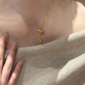 Detailed view of a 24K gold-plated rocking horse pendant necklace on a model's neck