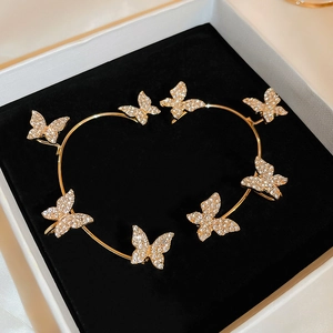 Detailed macro view of gold butterfly ear cuffs with white zircon stones on velvet