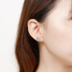 Detailed close-up of a silver crescent moon stud earring with star engravings on model ear