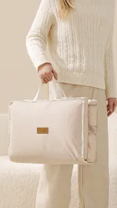 Dettaglio di una capiente borsa da viaggio beige con tasca laterale e inserto in pelle