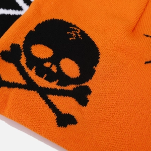 Macro shot of orange knit beanie texture with black skull and crossbones jacquard