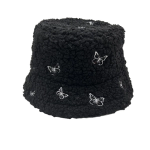 Close-up of black fleece bucket hat featuring intricate white butterfly embroidery detail