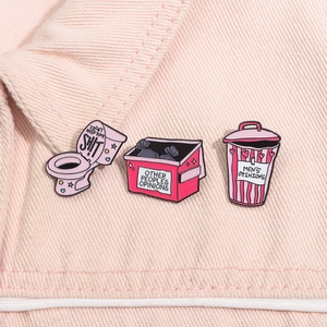 Vue détaillée de trois pin's émaillés roses sur denim avec des citations humoristiques