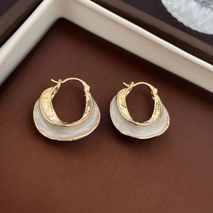 Macro shot of gold-plated oval hoop earrings with pearl accents and minimalist metal design