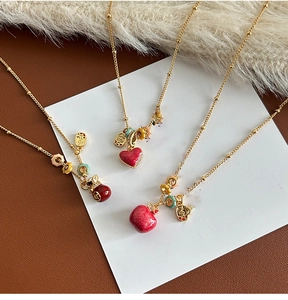 Detailed shot of 18k gold plated necklaces with red lucky bag and fruit charms
