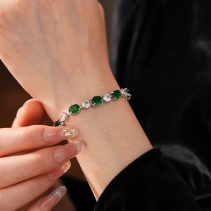 Détail du bracelet noeud asymétrique avec zircons verts et blancs sur le poignet