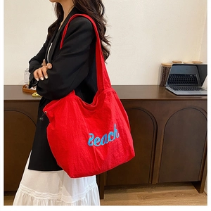 Close-up of bright red canvas tote bag with Beach print worn over the shoulder