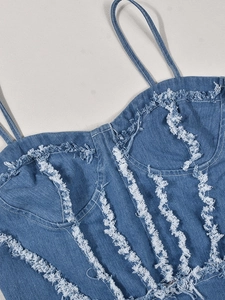 Détail d'un haut corset en jean bleu avec bords effilochés blancs et coutures