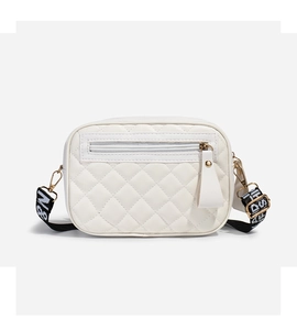 Close-up of white quilted crossbody bag featuring a patterned strap and white tassel detail