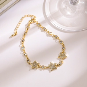 Detailed close-up of gold star charms and zircon inlay on a Cuban chain bracelet