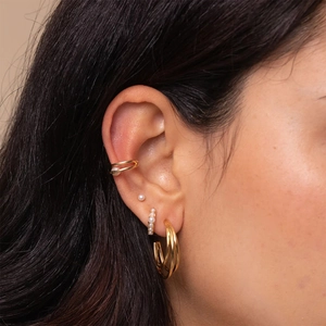 Close-up of elegant gold pearl earrings and ear cuffs on a female model