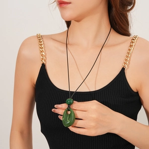 Detail shot of a dark green resin teardrop pendant with black cord on a female model
