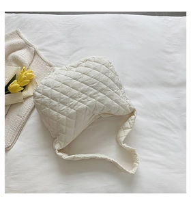 Close-up of cream quilted hobo bag featuring soft diamond texture on wrinkled fabric