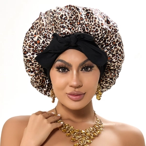 Close-up of leopard print satin sleep bonnet featuring a black bow and silky texture