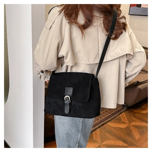 Close-up of black suede crossbody tote bag with metallic buckle detail on model