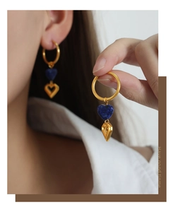 Detail view of gold titanium earrings featuring blue stone hearts and hollow heart charms