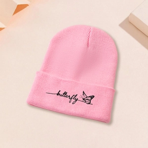 Gros plan sur un bonnet en maille rose avec broderie papillon noire et lettrage manuscrit
