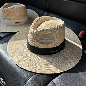 Detail of handmade raffia sun hats with metal brand tags and woven texture