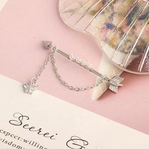 Detailed view of silver industrial barbell with butterfly charm and dangling chain
