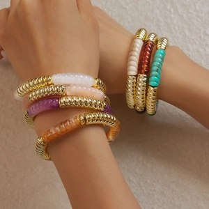 Gros plan de bracelets en perles acryliques empilés avec entretoises dorées pour femmes
