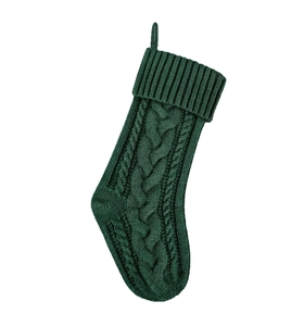 Dettaglio calza di Natale in maglia verde scuro con motivo a trecce e passante per appenderla