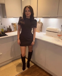 Fashionable black puff sleeve mini dress paired with black high boots in a kitchen setting