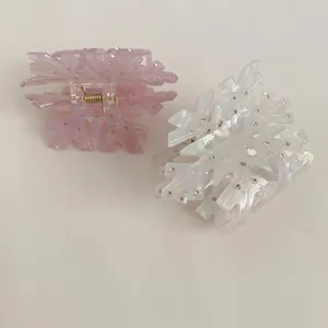 Snowflake hair claw clips in light pink and iridescent white with rhinestone accents
