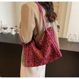 Fashionable rose red leopard print tote bag shown on a model in a cozy cafe setting