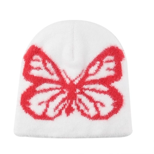 Close-up of the white knit beanie featuring a vibrant red butterfly pattern and soft texture