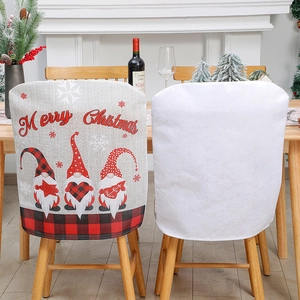 Christmas faceless gnome linen chair covers with red Merry Christmas text in festive dining room