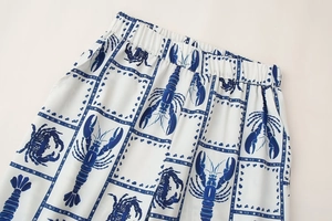Detail of white pants featuring blue lobster prints and elastic waistband design