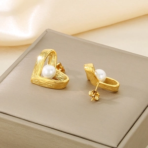 Close-up of vintage gold heart earrings with pearl inlay and textured metal finish