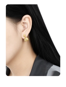 Detailed view of gold lava texture earrings with diamond inlay worn by a model