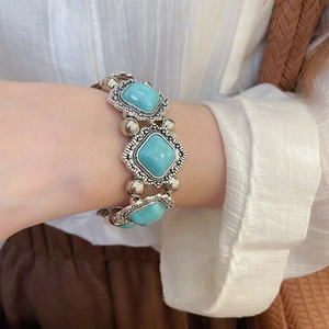 Detail of vintage silver metal bracelet with turquoise-style square stones and engravings