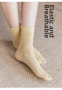 Detail of light yellow lace mesh socks with vintage openwork and wavy ruffled cuffs