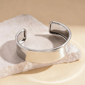 Macro shot of wide open cuff bracelet with polished silver mirror finish on stone stand
