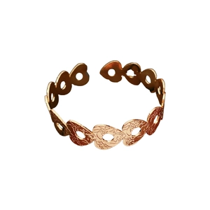 Golden heart-shaped cutout open ring with vintage embossed patterns on white background