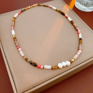Detail of bohemian pearl necklace with colorful beads and golden spacers on jewelry pad
