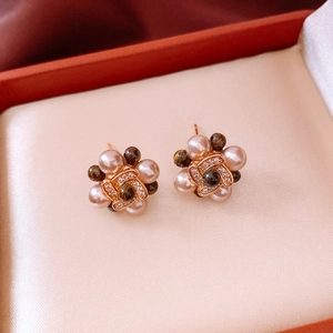 Macro shot of 18k rose gold plated flower stud earrings with pearls and crystals