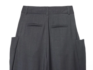 Detail view of charcoal grey wool pants showing back waistband loops and welt pockets