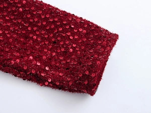 Dettaglio macro del tessuto tweed rosso con paillettes e texture di frange